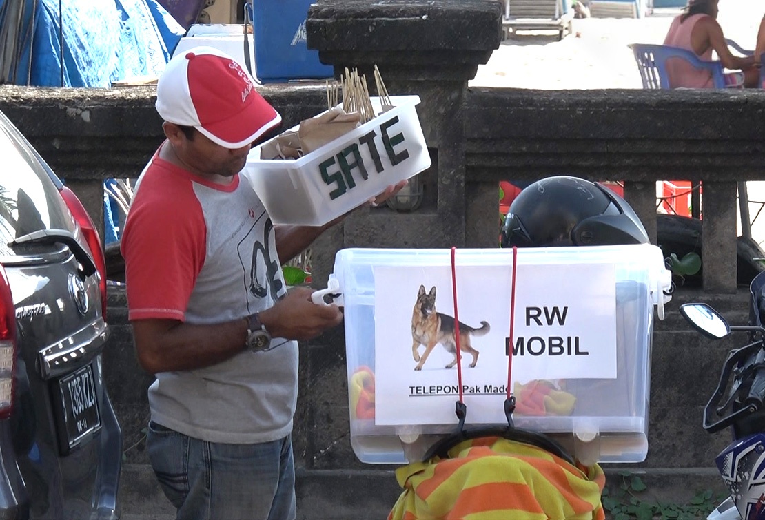 A mobile meat vendor prepares to sell dog meat ‘satay sticks’ to tourists.